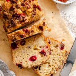 A loaf of cranberry apple bread with three slices cut.