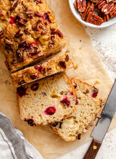 A loaf of cranberry apple bread with three slices cut.