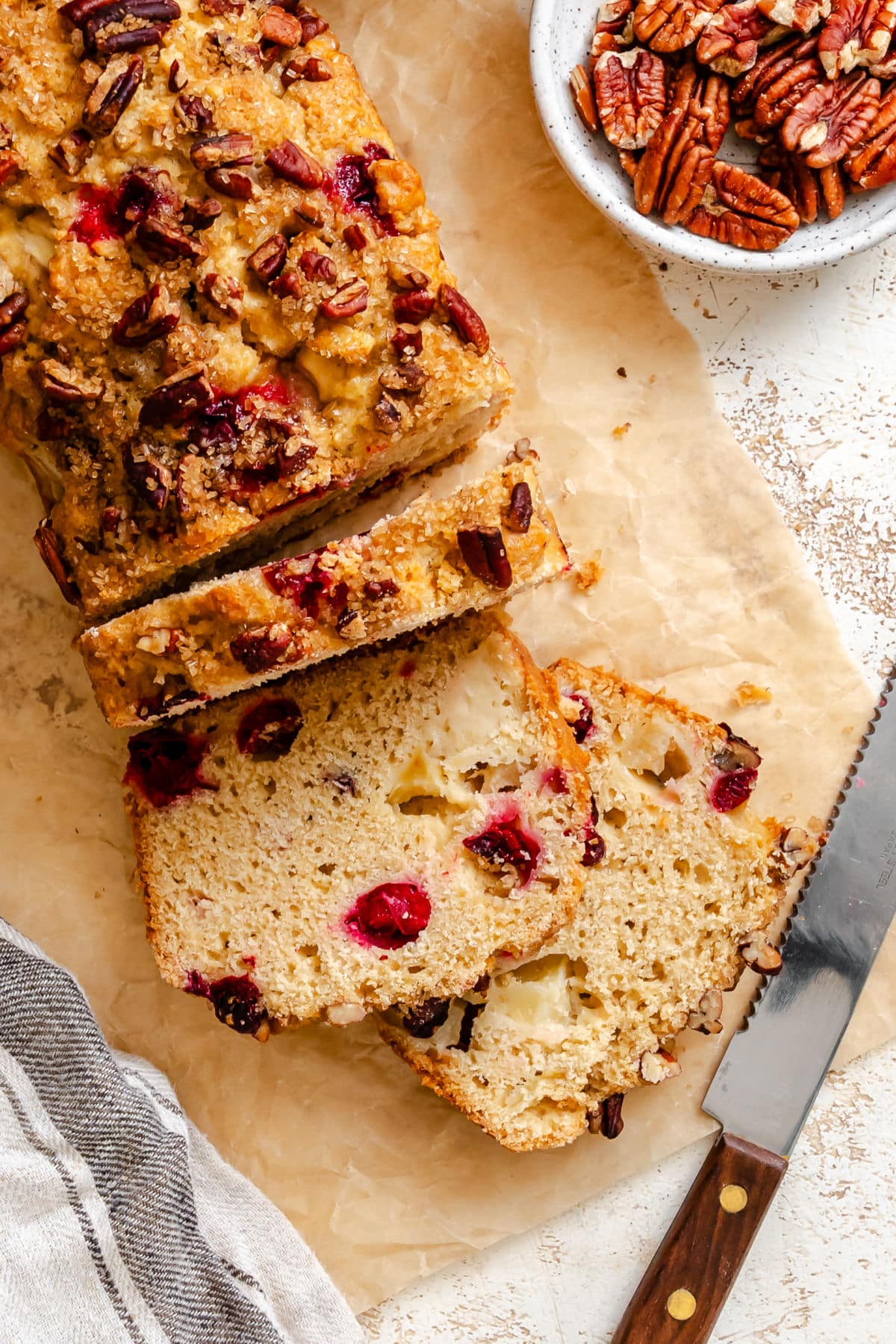 A loaf of cranberry apple bread with three slices cut.