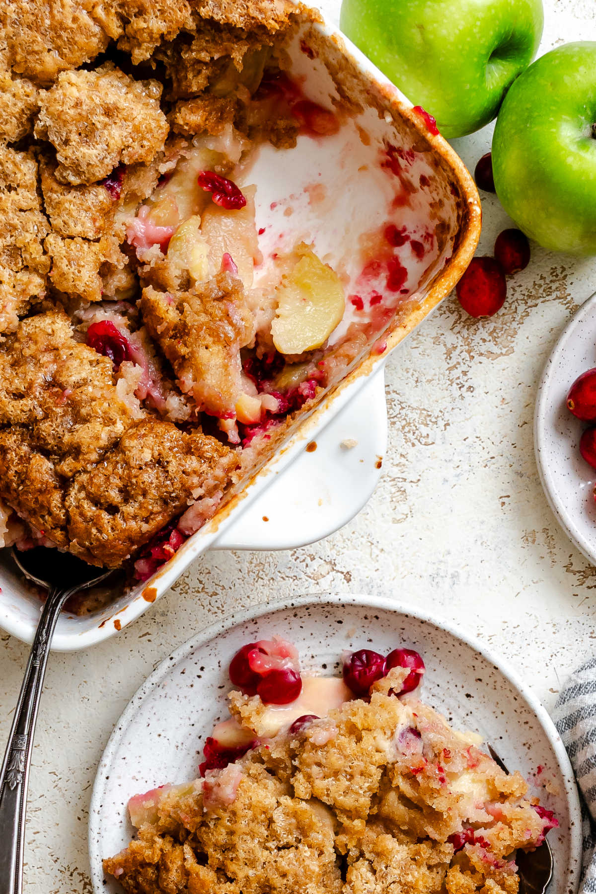 A pan of cranberry apple cobbler with part of the pan scooped out.