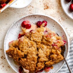 A plate of cranberry apple cobbler next to the pan.