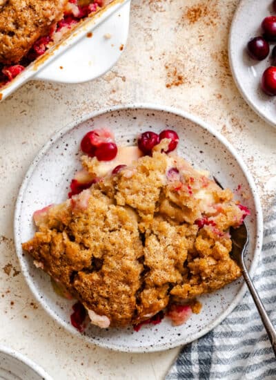 A plate of cranberry apple cobbler next to the pan.