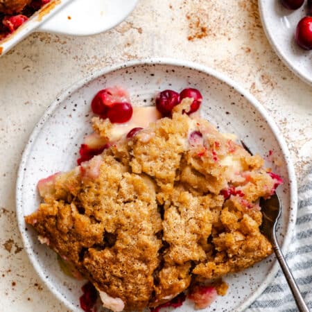 A plate of cranberry apple cobbler next to the pan.