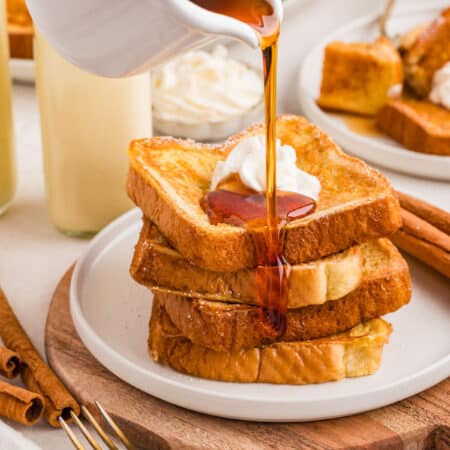 Syrup pouring onto a stack of eggnog French toast.