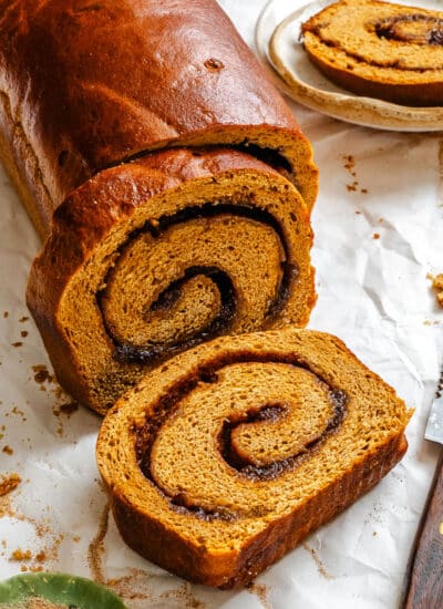 A slice of gingerbread cinnamon swirl bread lying next to the loaf.