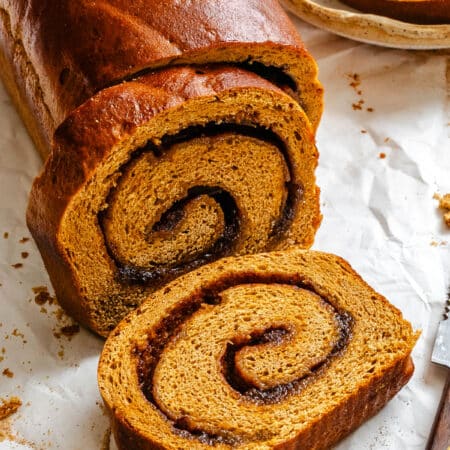 A slice of gingerbread cinnamon swirl bread lying next to the loaf.