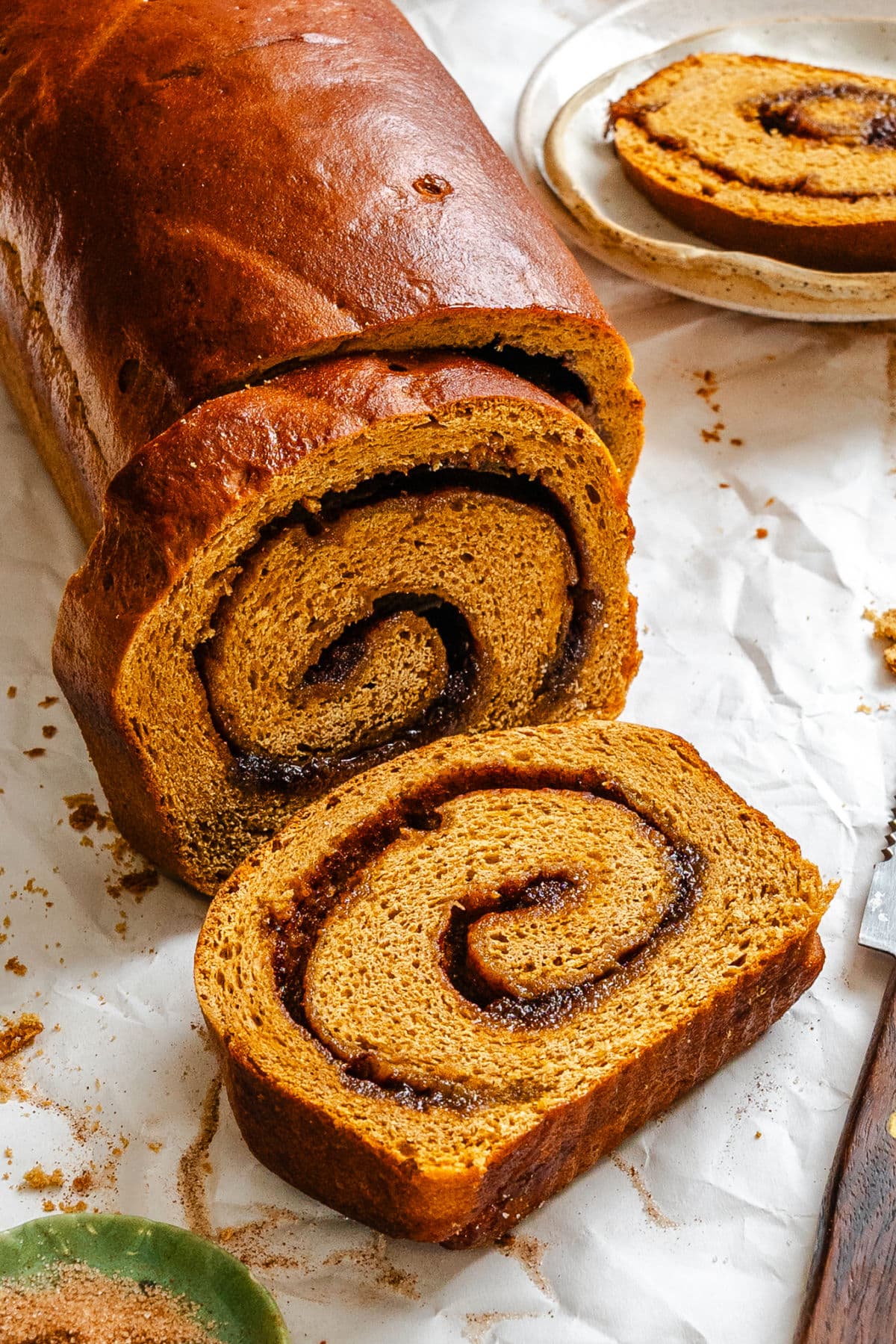 A slice of gingerbread cinnamon swirl bread lying next to the loaf.