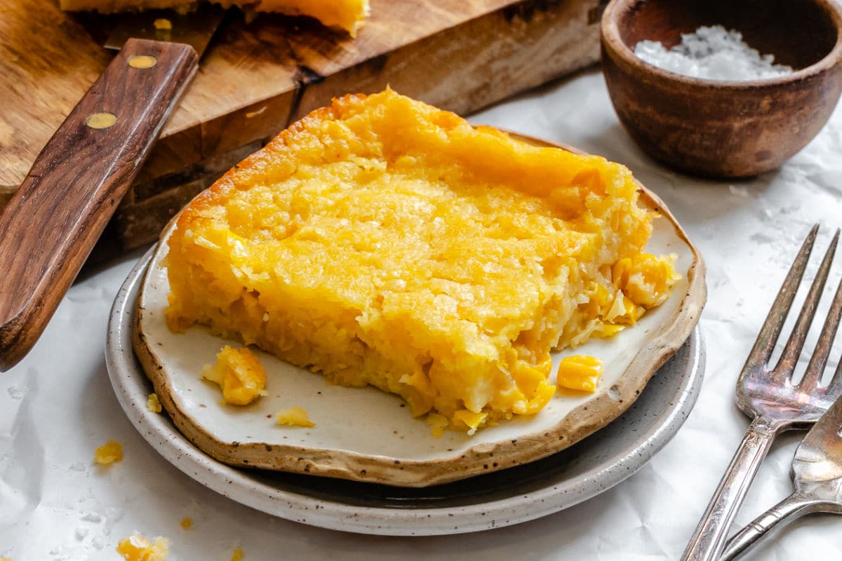A slice of Jiffy corn casserole on stacked plates next to crossed forks. 