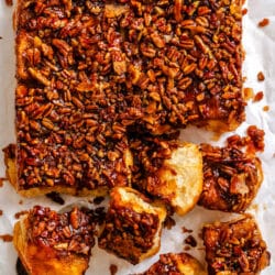 A tray of overnight sticky buns with some of the buns at an angle on the bottom.