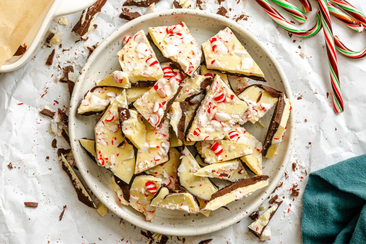 A plate of peppermint bark next to a green kitchen linen.