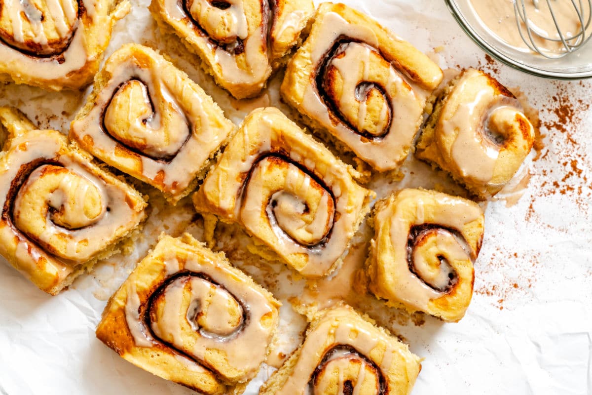Potato cinnamon rolls next to a bowl of cinnamon icing. 