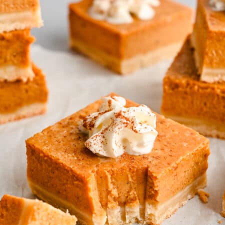 A piece of pumpkin pie bar with a bite missing.