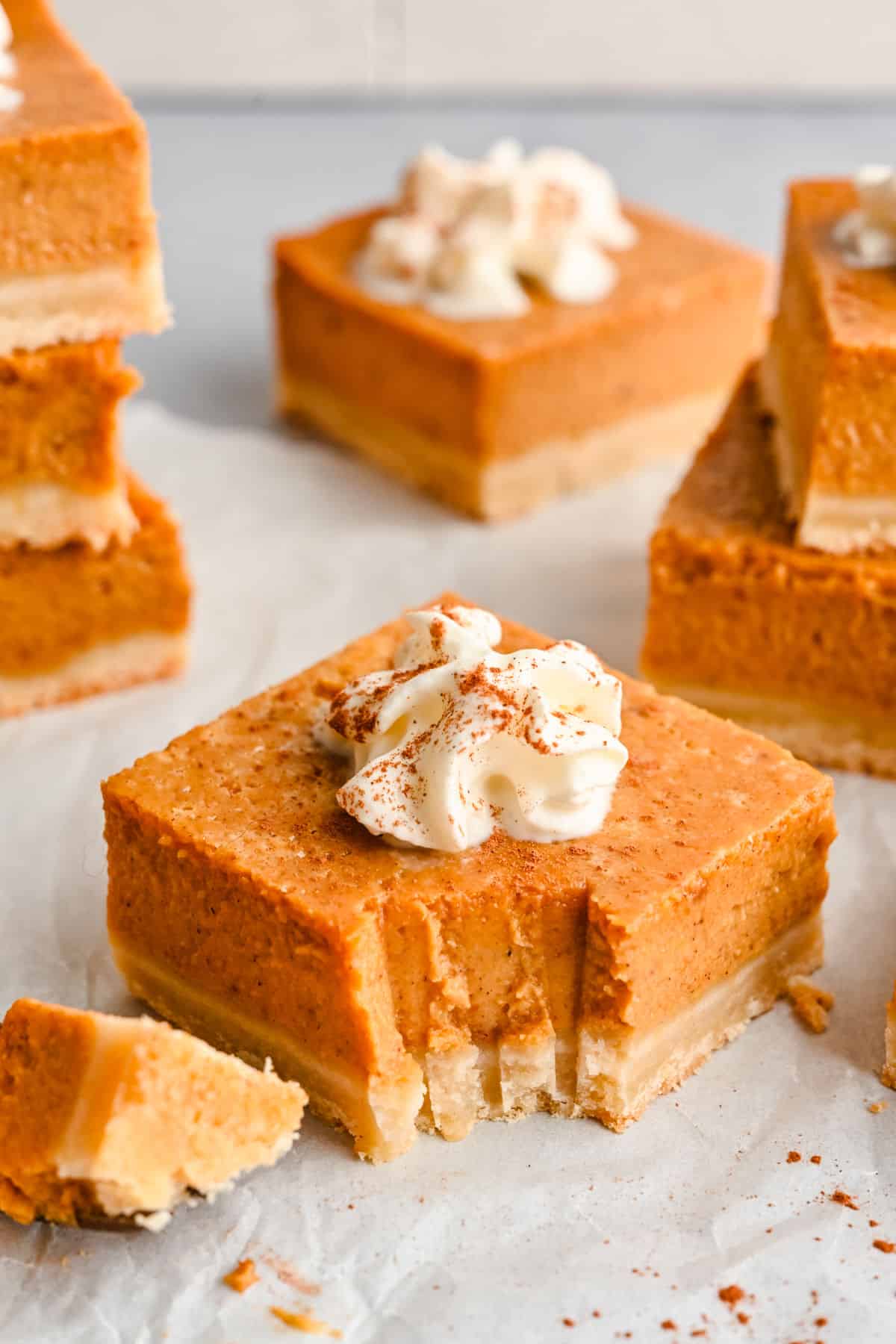 A piece of pumpkin pie bar with a bite missing. 