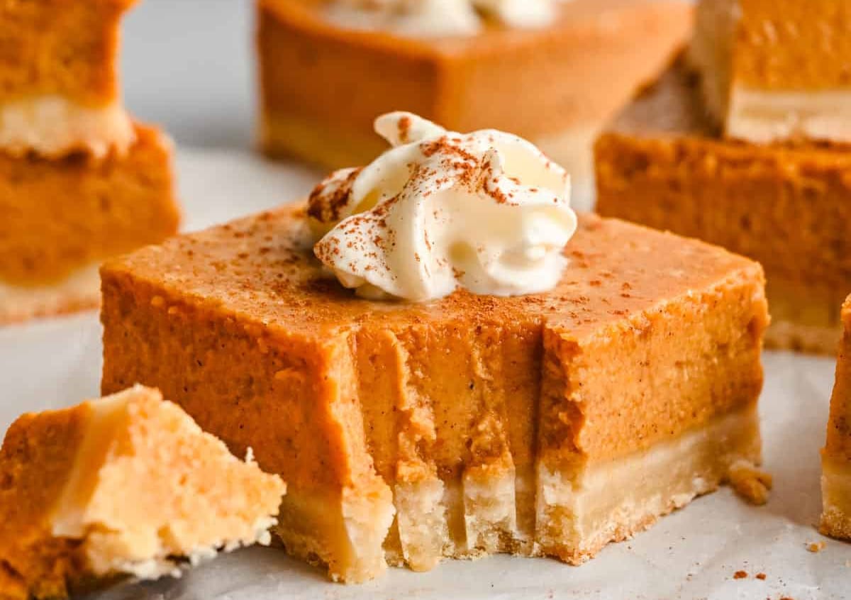 A piece of pumpkin pie bar with a dollop of whipped cream. 