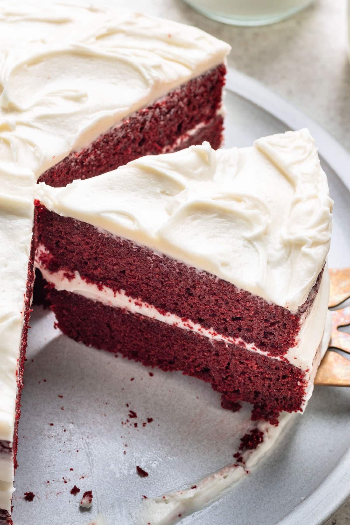 A slice of red velvet layer cake next to the cake.