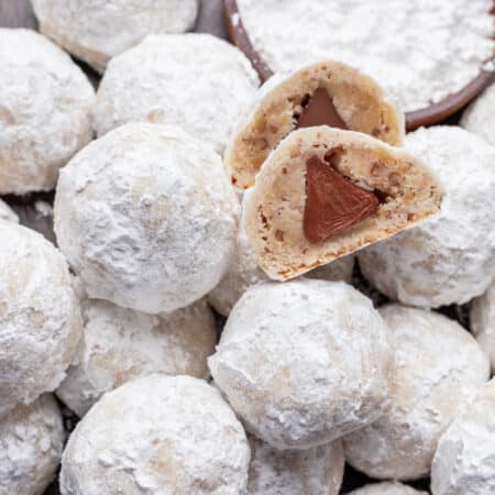 A snowball kiss cookie that's been cut in half showing the kiss inside the cookie.