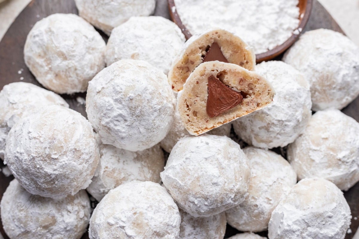 A snowball kiss cookie that's been cut in half showing the kiss inside the cookie.