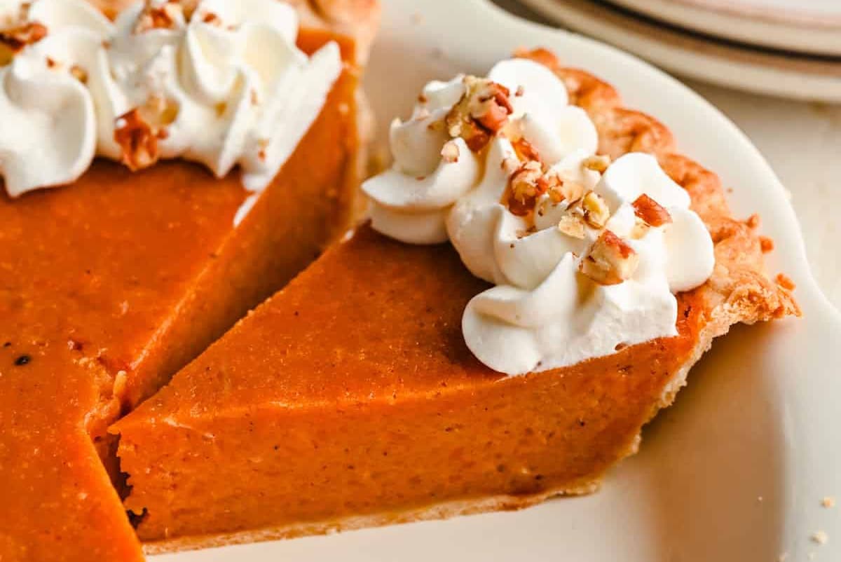 A slice of sweet potato pie in a pie pan.