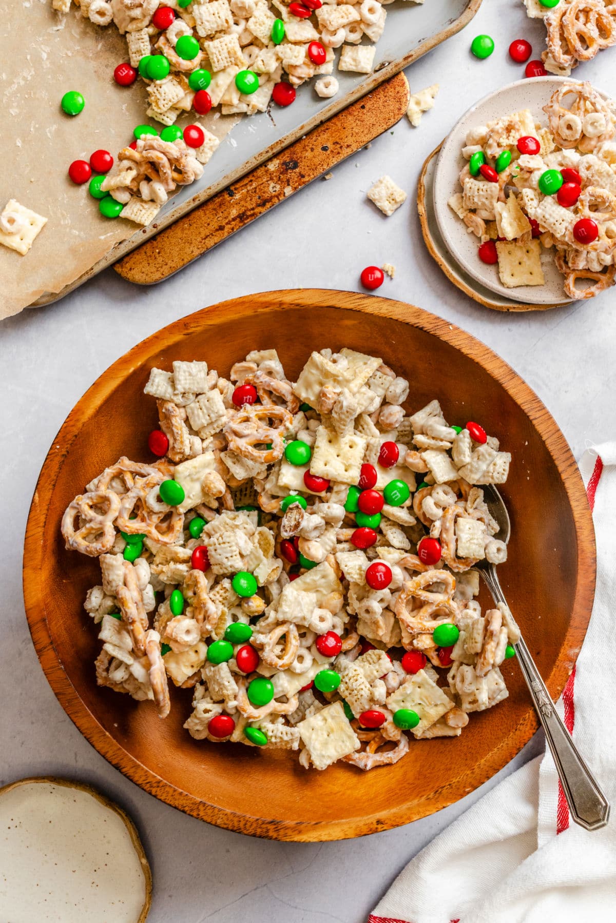 A bowl of Christmas chex mix next to a dish cloth.