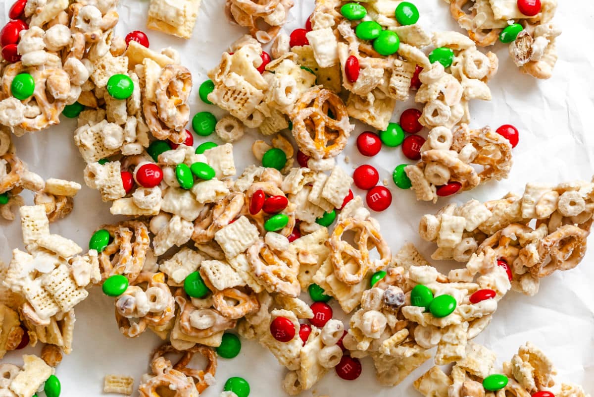 Christmas Chex mix spread out on a piece of white parchment paper.