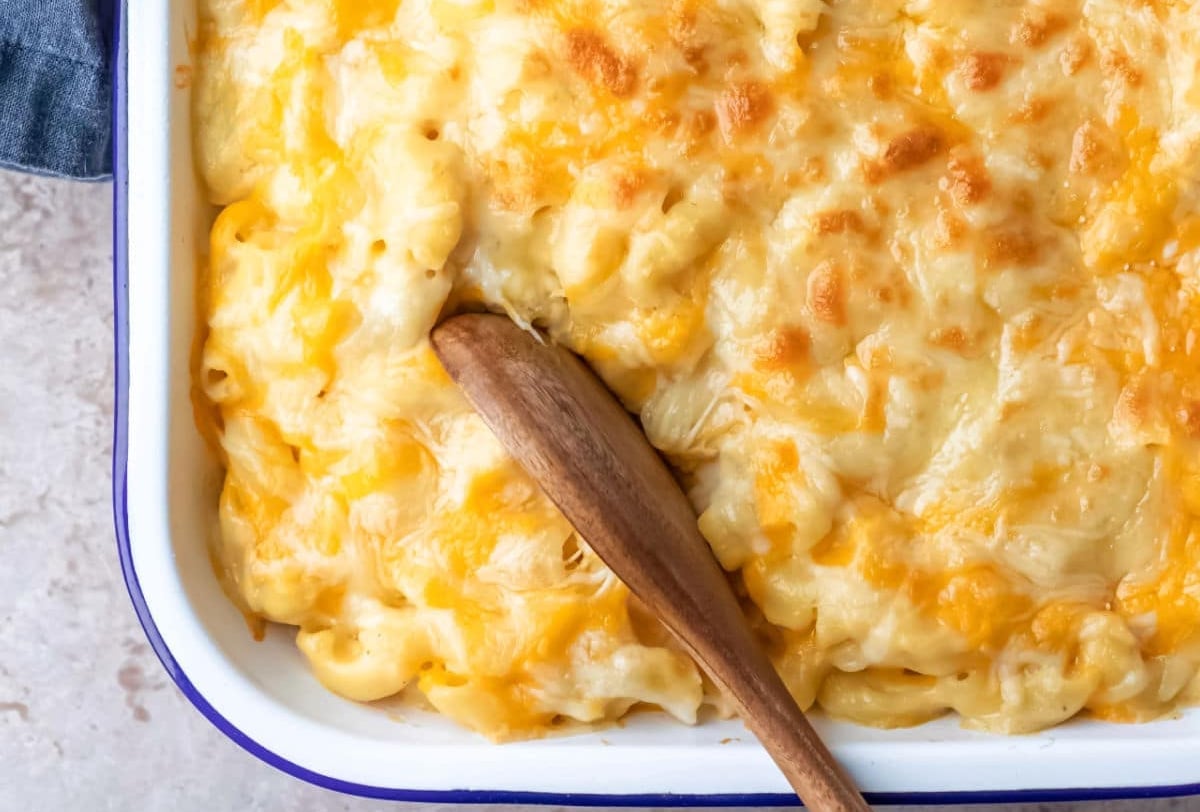 A wooden spoon in a pan of baked macaroni and cheese.