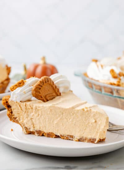 A slice of no bake pumpkin pie topped with whipped cream and a Biscoff cookie.