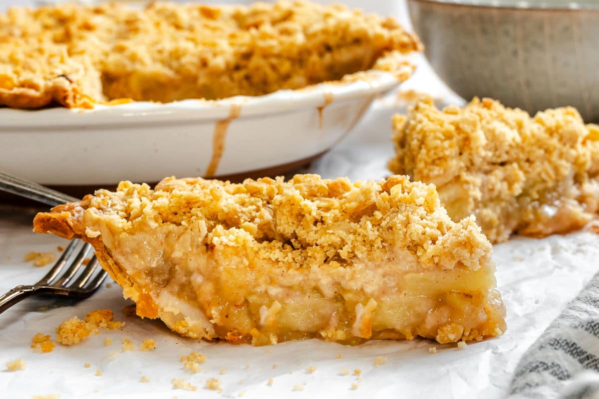 A slice of apple crumble pie next to the pie. 