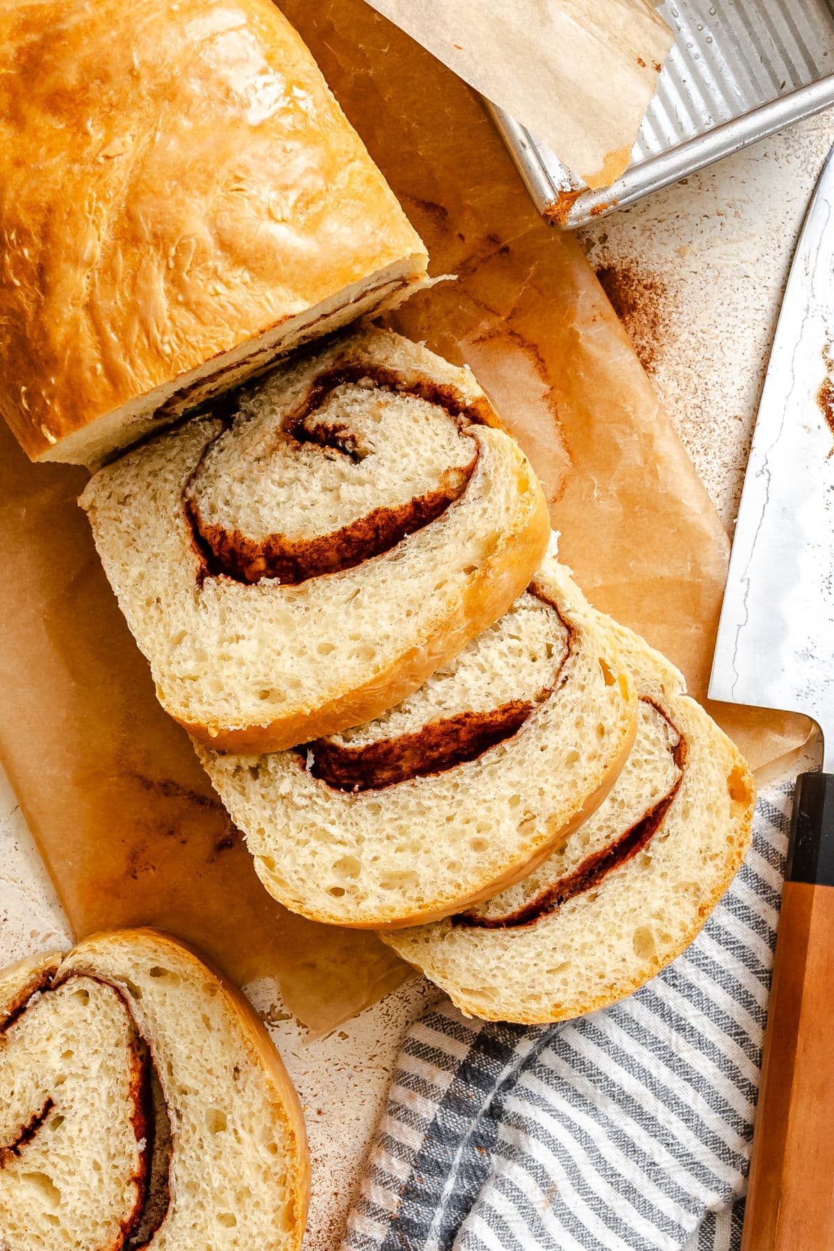 A loaf of partially sliced cinnamon bread on a wooden cutting board. 