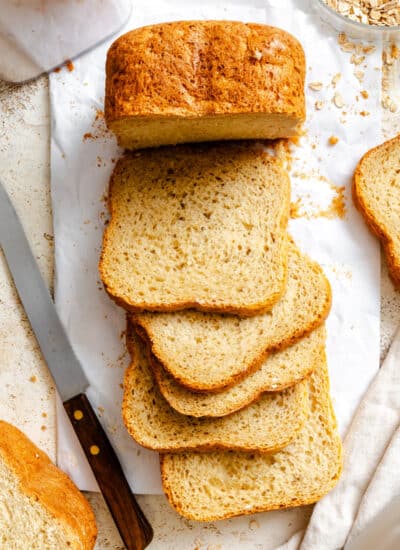 Slices of bread machine honey oat bread next to the partially cut loaf.