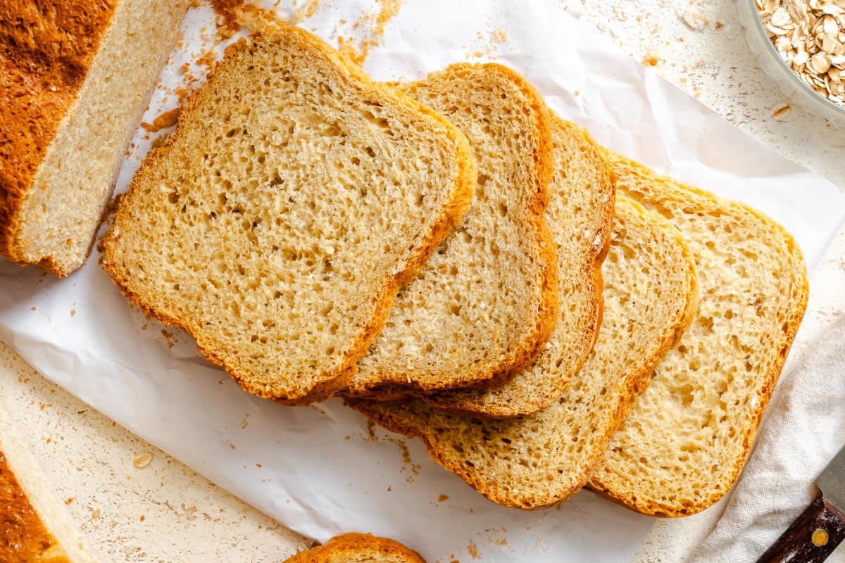 Slices of bread machine honey oat bread on a cutting board. 
