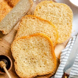 Three slices of honey white bread next to the loaf.