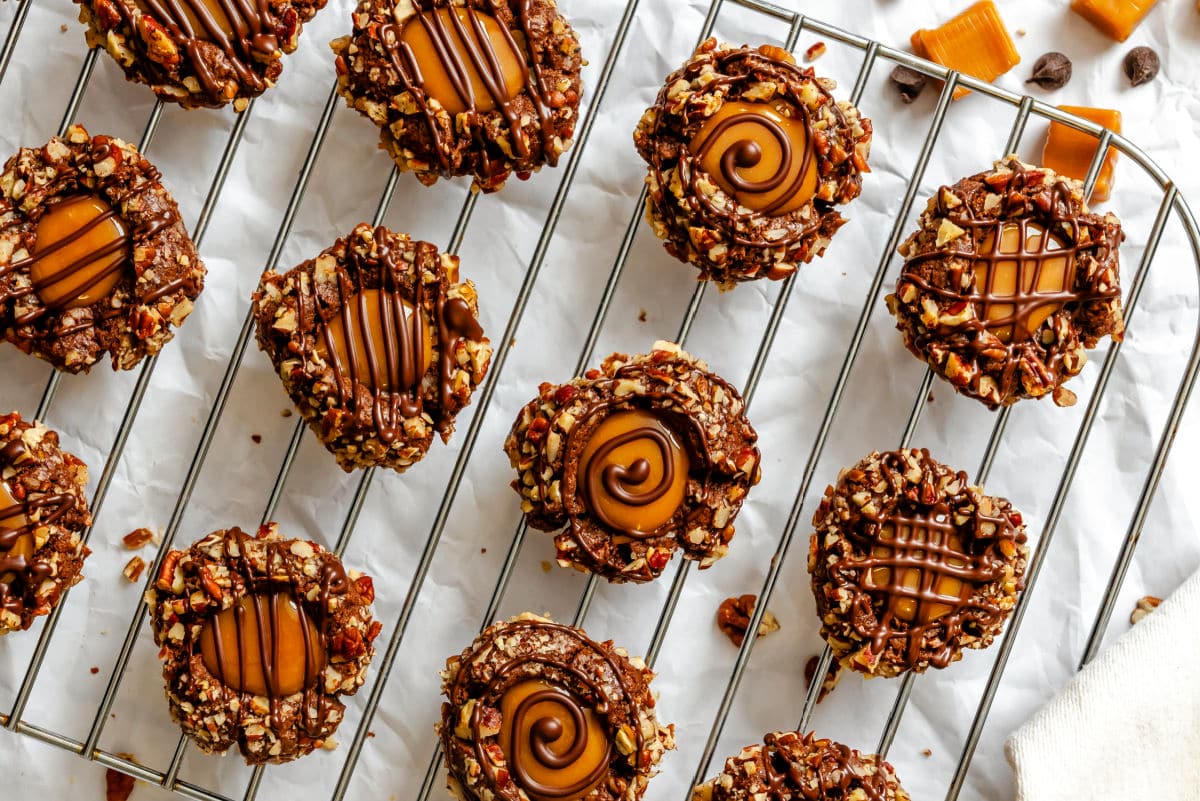 Chocolate caramel thumbprint cookies on a wire cooling rack. 