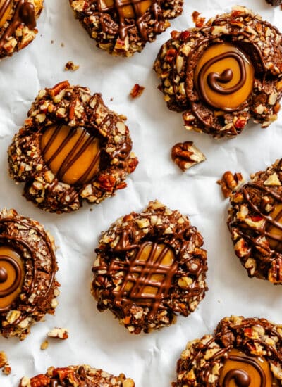 Chocolate caramel thumbprint cookies on a piece of white parchment paper.