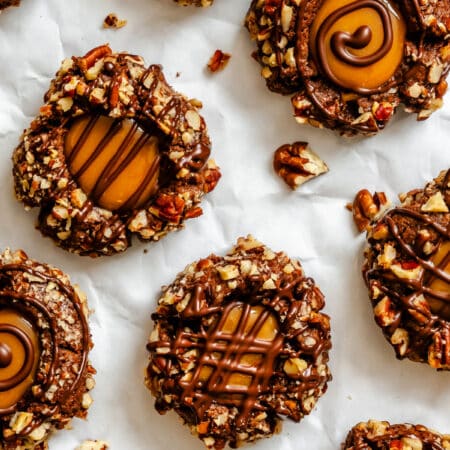 Chocolate caramel thumbprint cookies on a piece of white parchment paper.