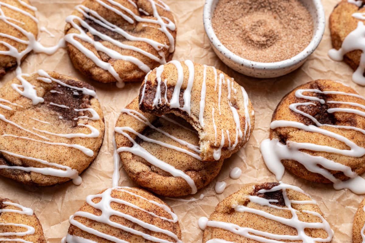 A cinnamon roll cookie with a bite missing on top of another cookie.