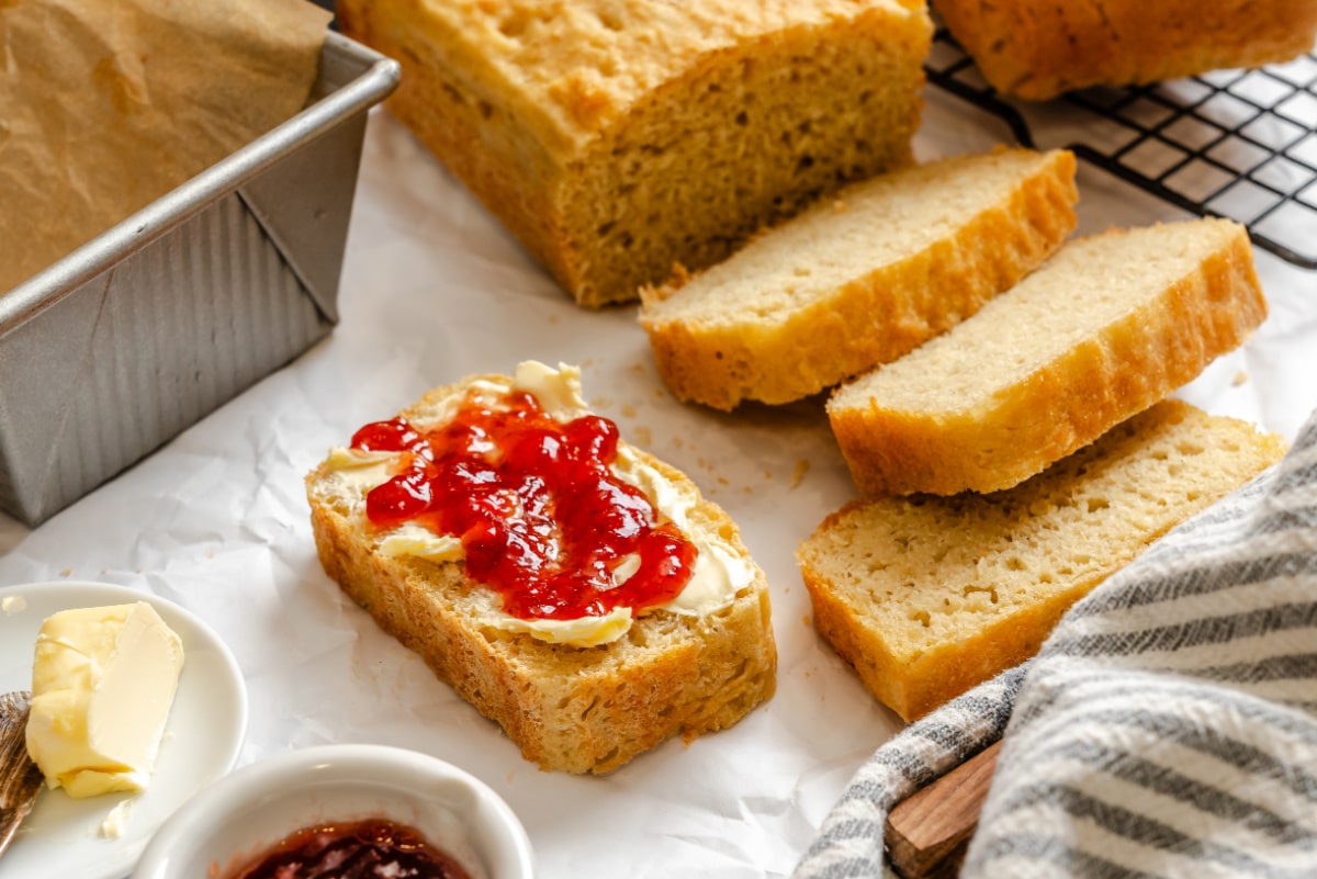 Slices of English muffin bread next to the loaf and pan.