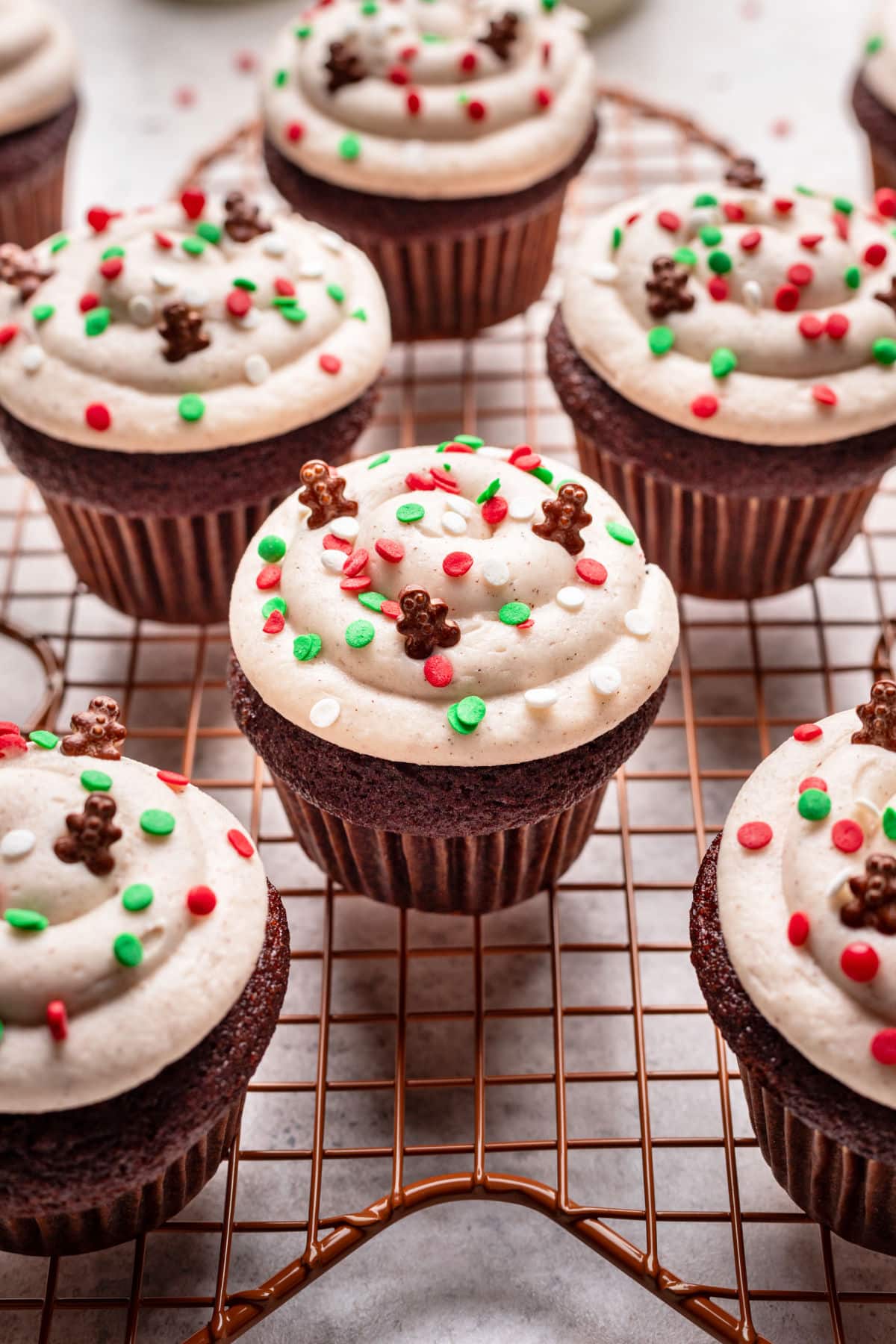 Decorated gingerbread cupcakes on a wire cooling rack.