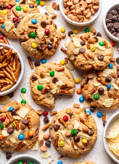 Overlapping kitchen sink cookies with dishes of chocolate chips, pretzels, and M&Ms in between.