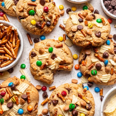 Overlapping kitchen sink cookies with dishes of chocolate chips, pretzels, and M&Ms in between.