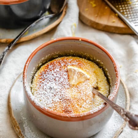 A lemon pudding cake in a ramekin with a spoon in it.
