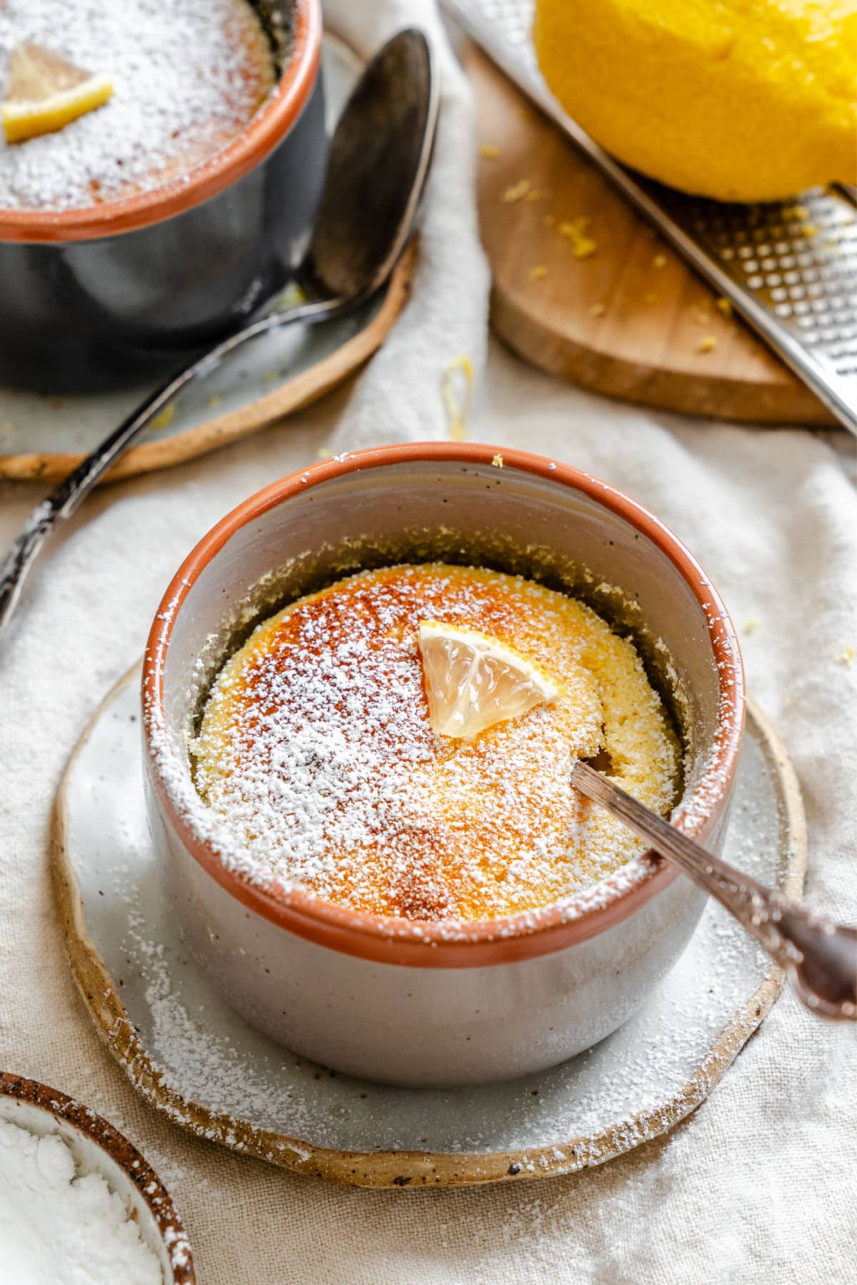 A lemon pudding cake in a ramekin with a spoon in it.