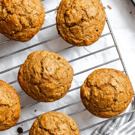 Refrigerator bran muffins on a wire cooling rack next to a kitchen towel.