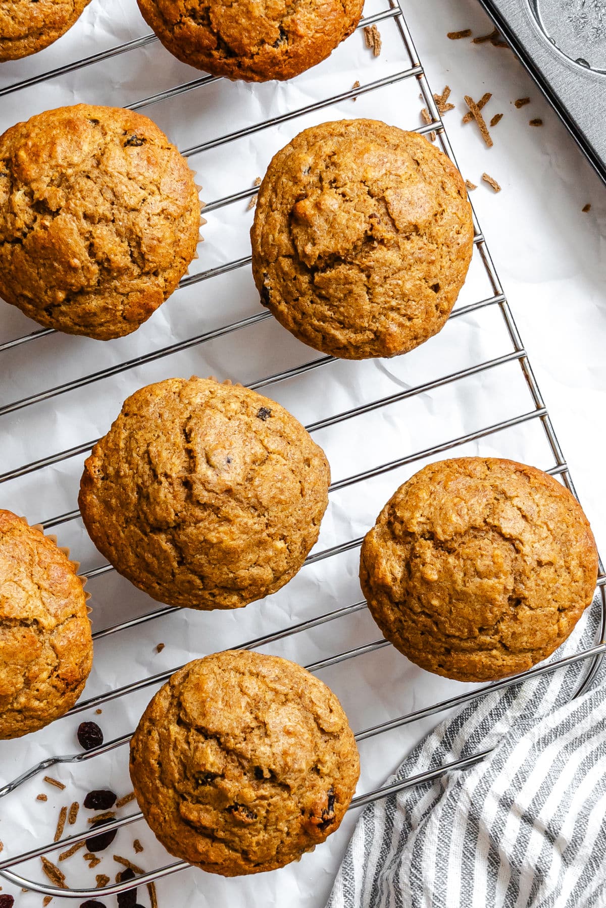 Refrigerator bran muffins on a wire cooling rack next to a kitchen towel.