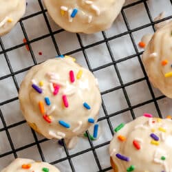 Frosted baked sugar cookie donut holes on a wire cooling rack.