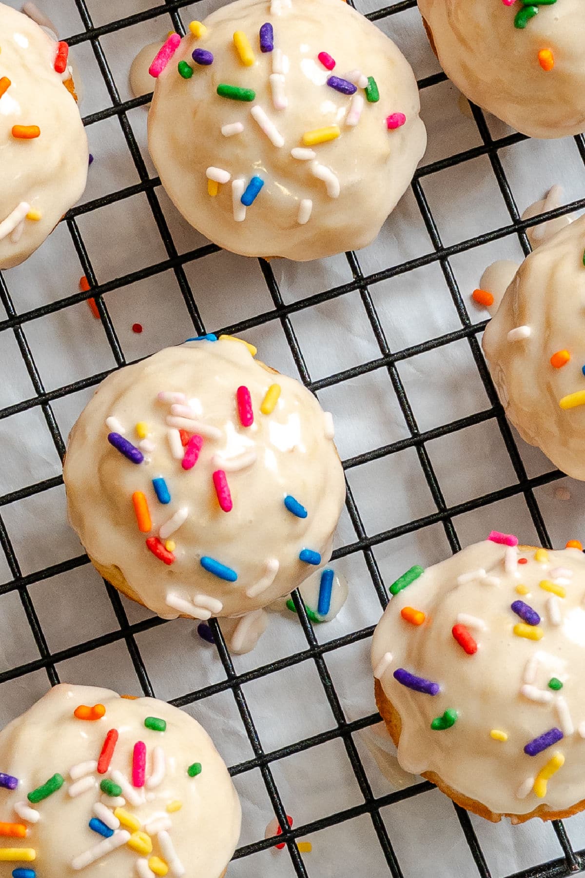 Frosted baked sugar cookie donut holes on a wire cooling rack.