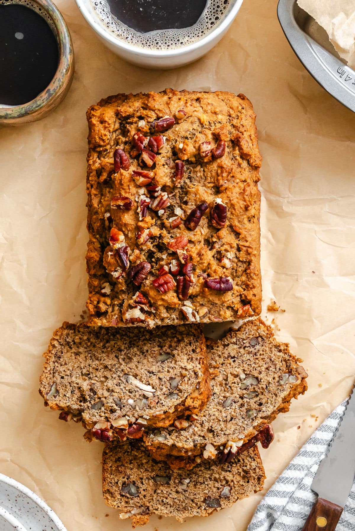 Three slices of whole wheat banana bread overlapping in front of to the loaf.