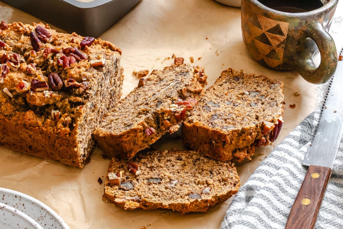 Slices of whole wheat banana bread next to a mug of coffee.