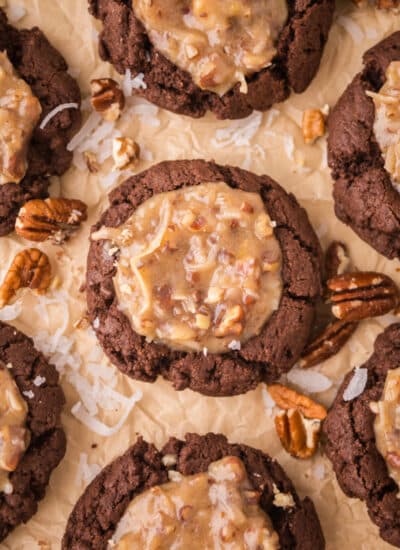 Rows of German chocolate thumbprint cookies on brown parchment paper.