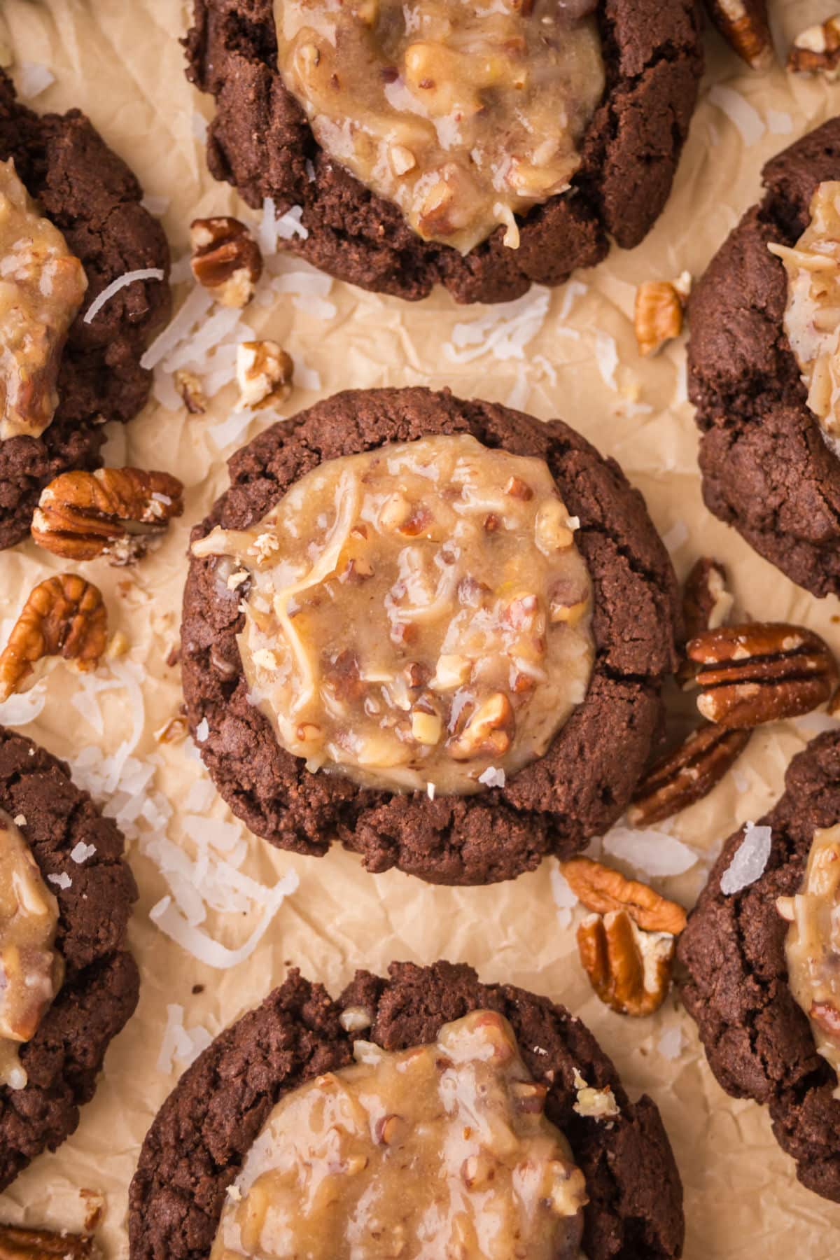 Rows of German chocolate thumbprint cookies on brown parchment paper.