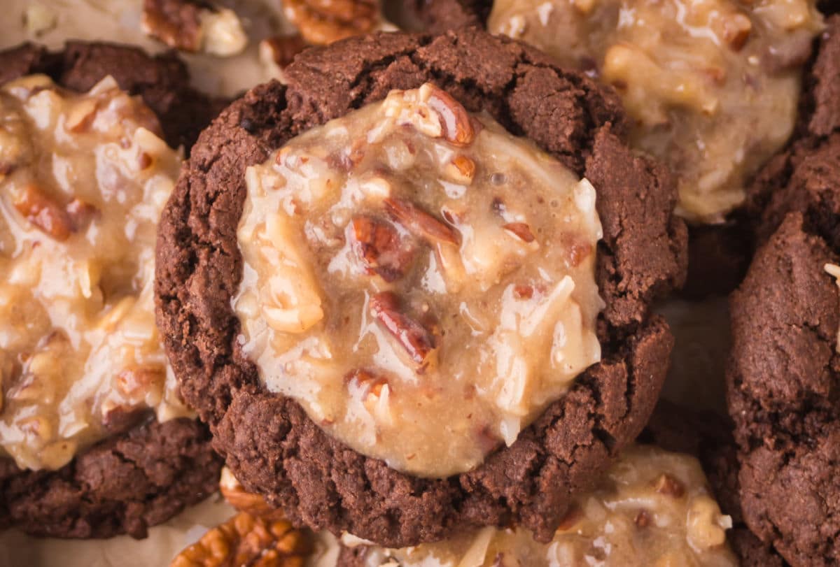 A stack of overlapping German chocolate thumbprint cookies.